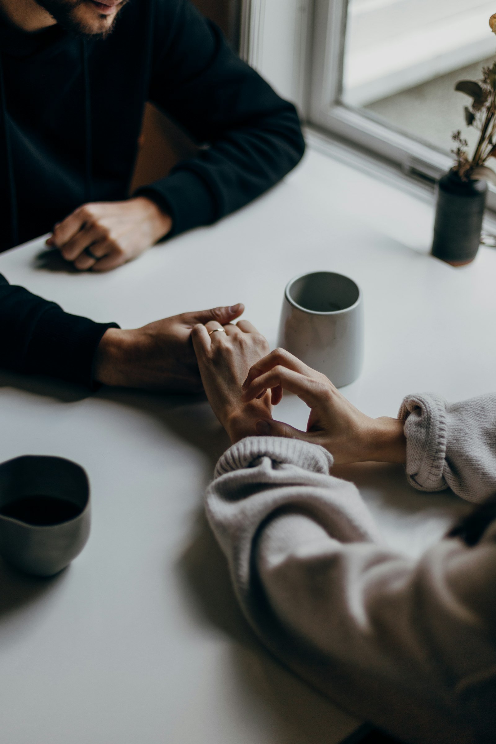 Twee mensen die elkaars hand vasthouden aan een tafel